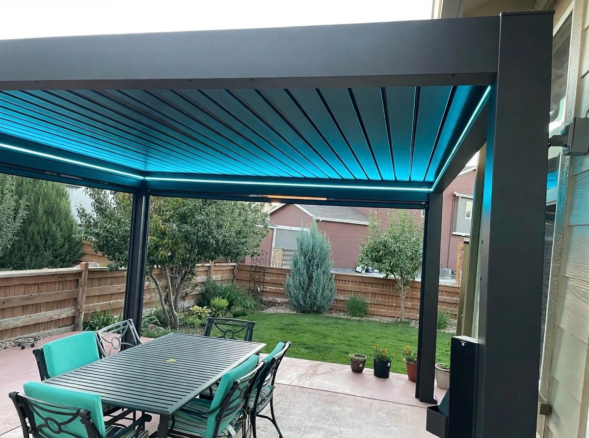 Pergola at dusk with teal LED light built into the beams over a dining set