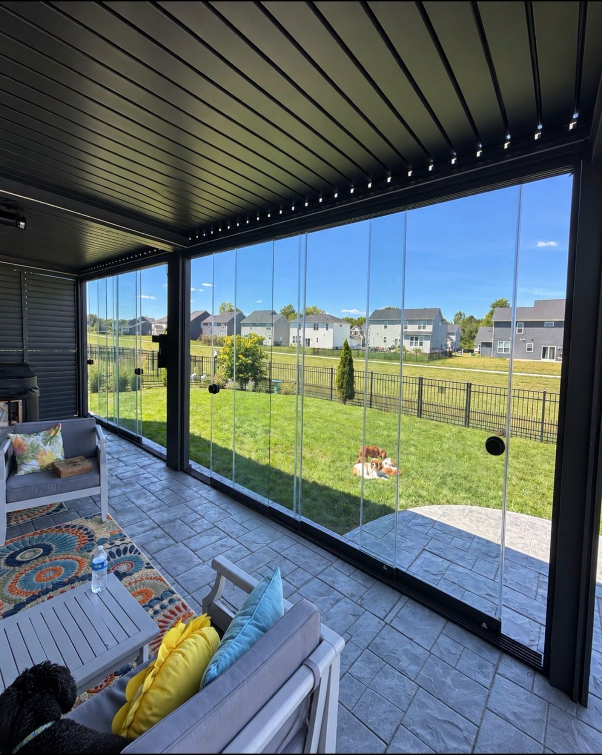 Inside a pergola with full glass sliding walls looking out over a green lawn