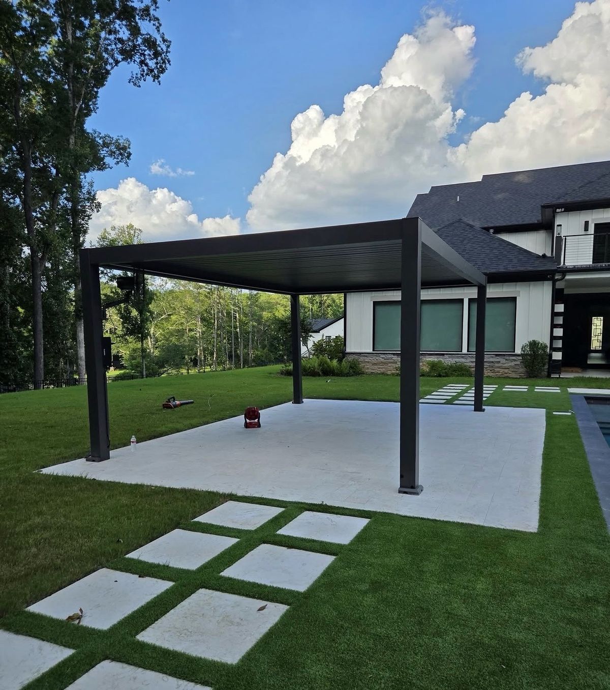 Large dark pergola covering a whole patio slab, house and lawn behind it