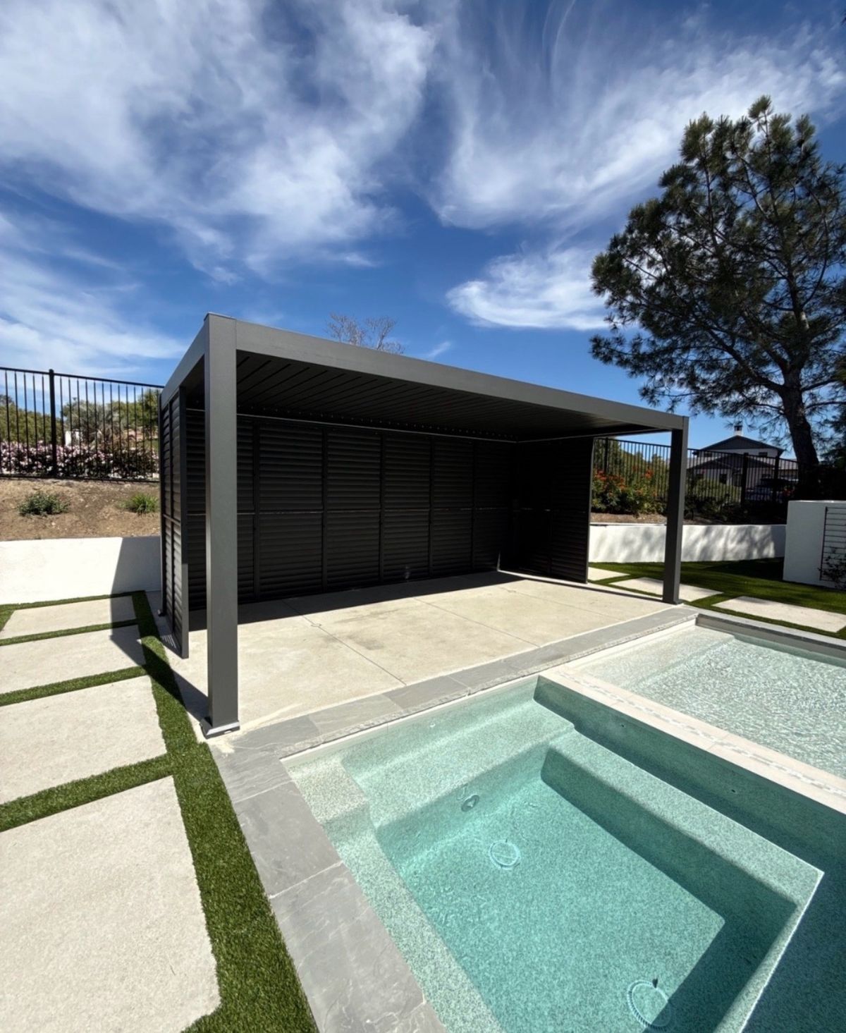 Gray pergola with slat walls beside a small plunge pool